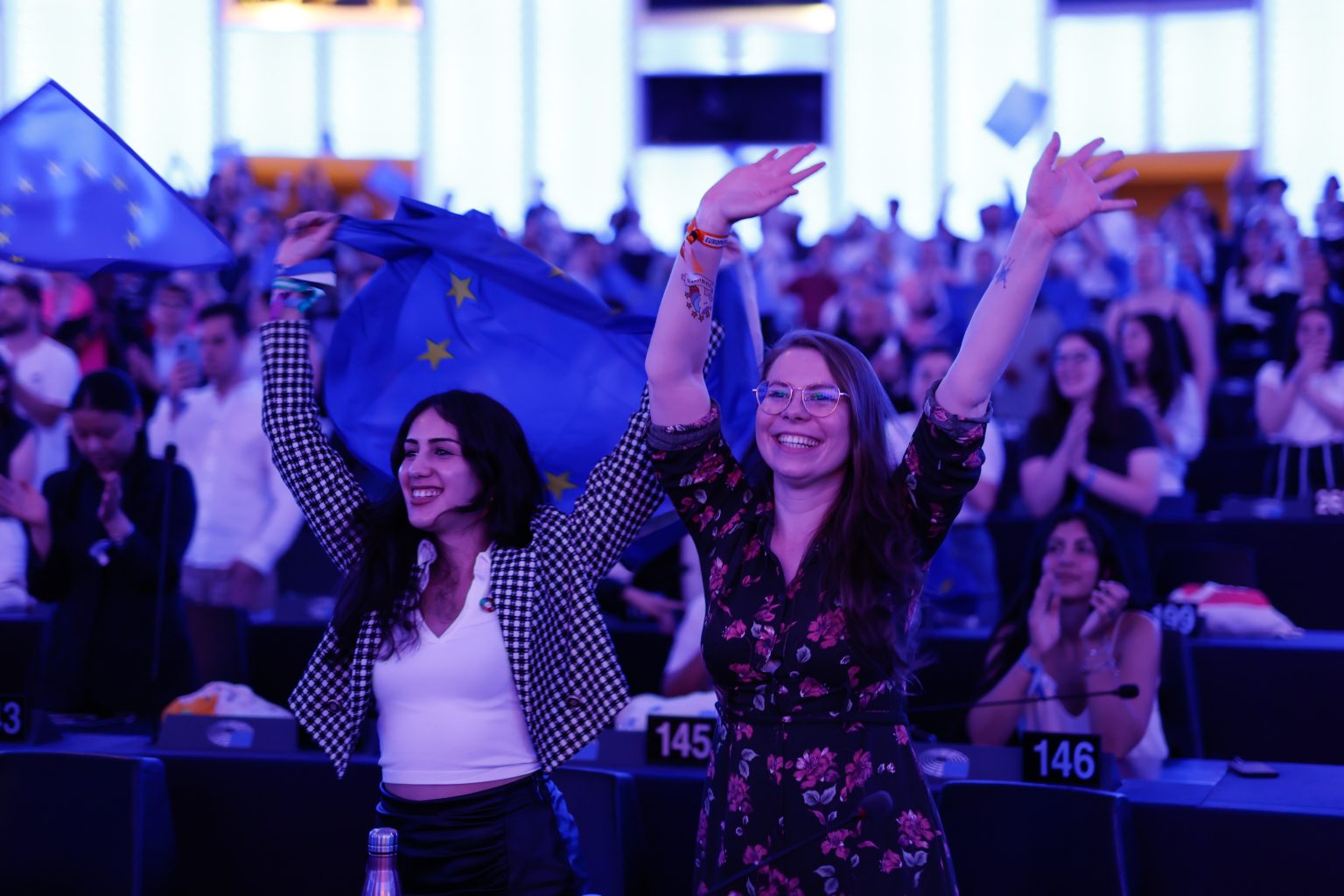 EYE 2023 indoor event. The image shows two girls with hands in the air smiling.